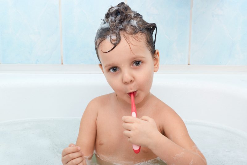 close-up-portrait-carming-little-girl-cleans-her-teeth-with-red-toothbrush